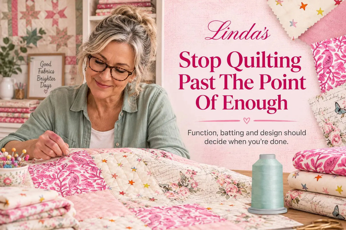 Quilter in a sage-green shirt sewing a pink, cream and floral patchwork quilt at a table in a bright studio — deciding when the quilting is finished