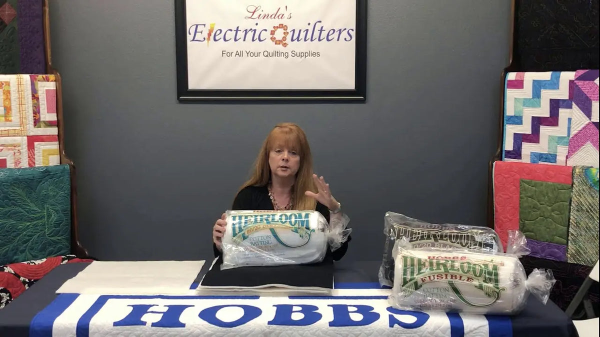 Stephanie Hackney of Hobbs Bonded Fibers showing the four versions of Heirloom 80/20 batting: natural, bleached, black and fusible