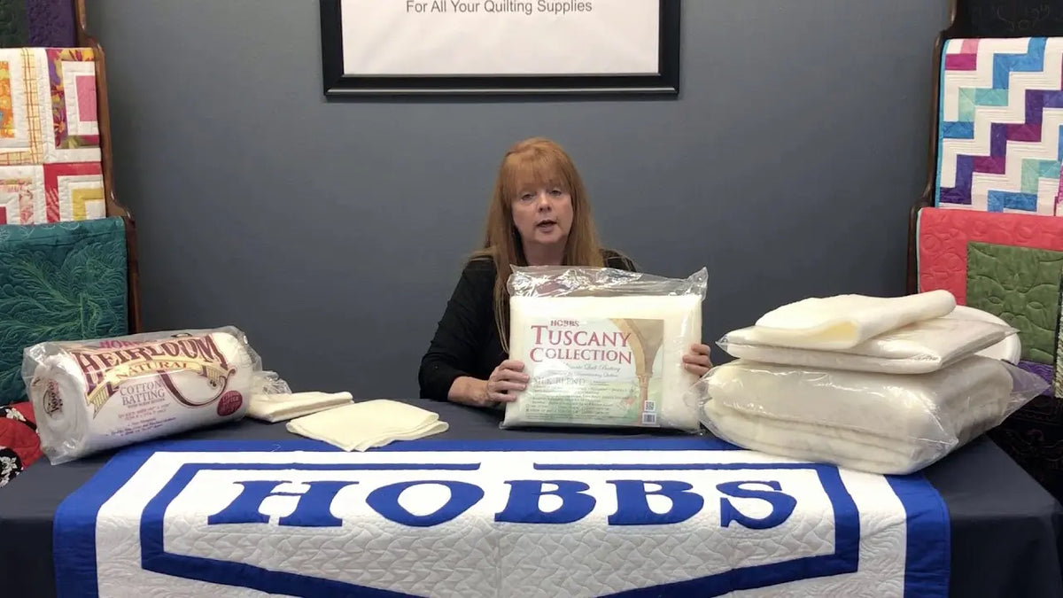 Stephanie Hackney of Hobbs Bonded Fibers holding batting samples while explaining how to choose quilt batting