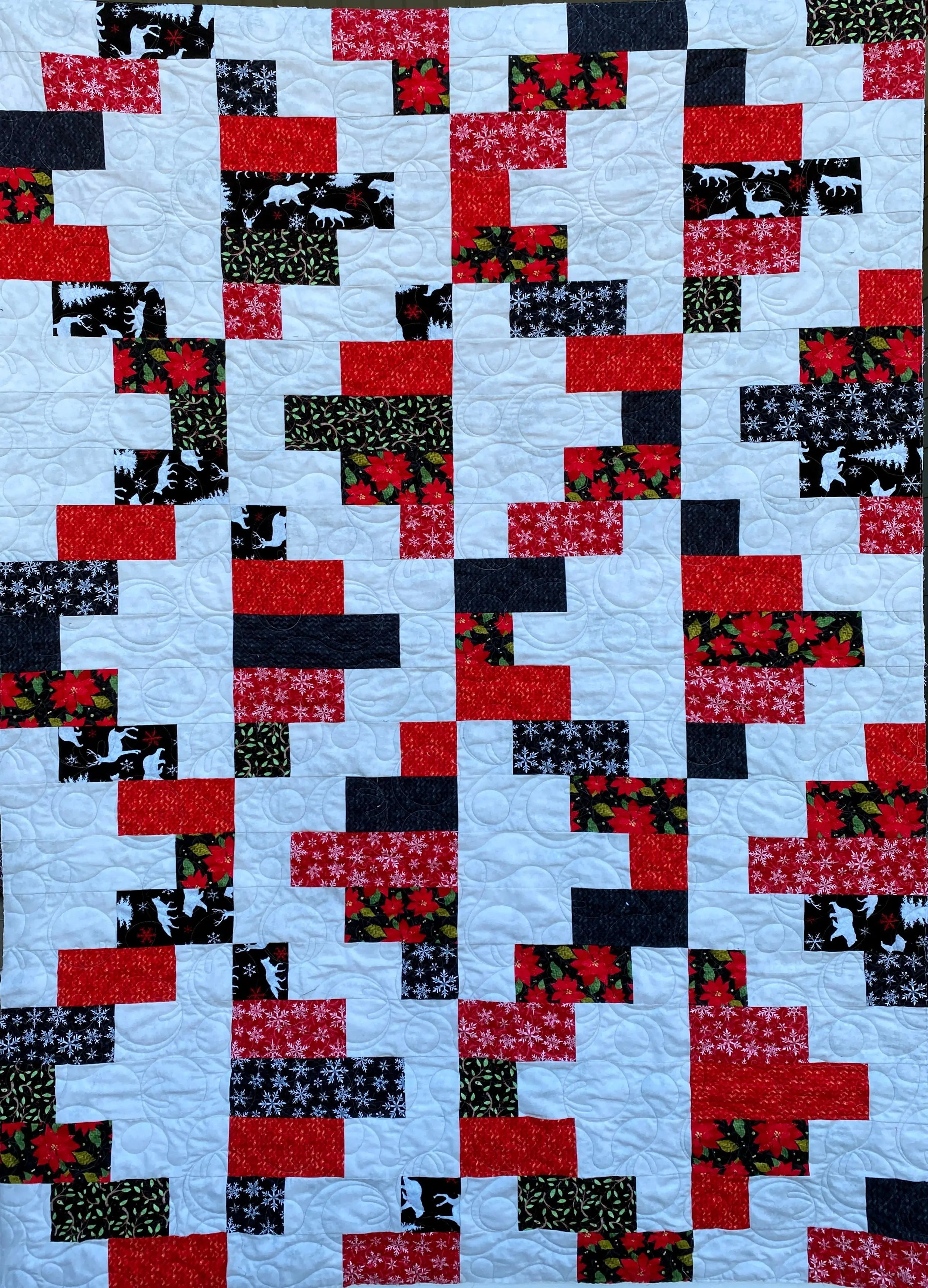 Quilt with a geometric pattern of red, black, and white squares on a blue background